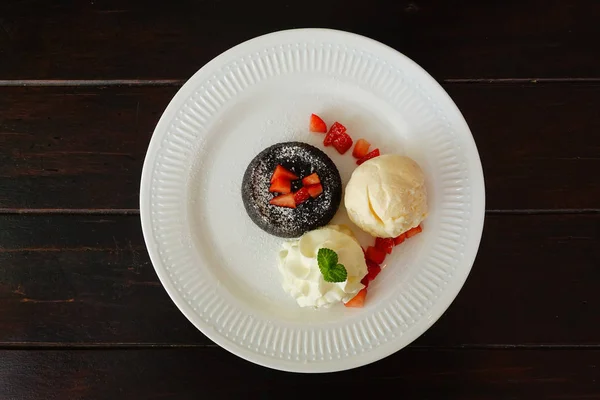 chocolate lava cake set with ice cream and strawberry on white plate