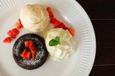 Dondurma ve beyaz tabakta çilekli çikolatalı kek.