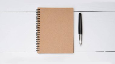 Beyaz ahşap arka planda defter ve kalemi kapat