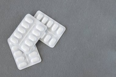 Gri arka planda beyaz plastik pakette bir sürü ilaç ve ilaç var. Sağlık sigortası konsepti. Metin için boşluk.
