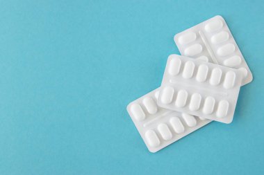 Mavi arka planda beyaz plastik pakette bir sürü ilaç ve ilaç var. Sağlık sigortası konsepti. Metin için boşluk.