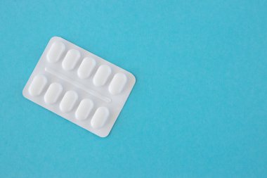 Mavi arka planda beyaz plastik pakette bir sürü ilaç ve ilaç var. Metin için sağlık konsepti wirth alanı.