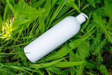 Yeşil çimlerde krema, merhem ya da yağ için beyaz plastik şişe. Kozmetik için doğa arkaplanı. 