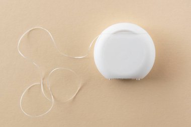 Ağız hijyeni için beyaz diş ipi ve bej arka planda sağlık dişleri ve metin için boşluk.