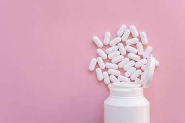 Pembe arka planda beyaz şişede bir sürü ilaç ve ilaç var. Sağlık sigortası konsepti. Metin için boşluk.