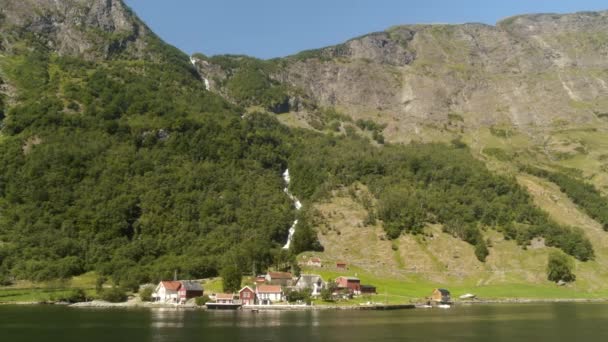 ノルウェーのフィヨルドにある巨大な滝の下の小さな町 ノルウェーの美しいフィヨルド 北ノルウェーのフィヨルドのこの美しいショットは Flam ノルウェーへの旅遊覧船から撮影されました — ストック動画