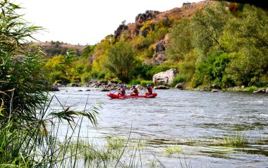 Kayalıklarda dağ gibi akan su. Kırmızı tekne. Rafting.