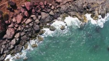 Kıyı kırmızı taşlarulaşan turkuaz deniz dalgaları havadan görünümü. Drone görünümü 4k Hindistan Gokarna Bal plaj.