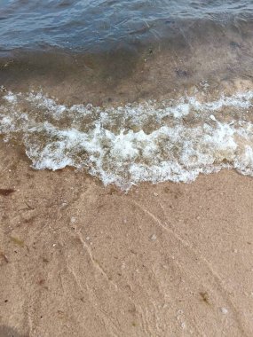 Yumuşak dalgaların sakin bir kumsalda yıkanması huzur ve doğal güzellik hissi veriyor..