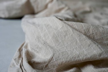 Bu çok güzel detaylı bir kumaş parçasının yakın plan görüntüsü rahat bir yatağa yerleştirilmiş, dokusunu ve renk çarşafını vurguluyor dağınık yatak düzenini bozuyor. 