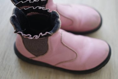 Güzel, ahşap bir zeminde, parlak renkleri ve yalın ayak tarzları için giyilmeyi ya da hayran olunmayı bekleyen büyüleyici bir çift pembe bot duruyor.