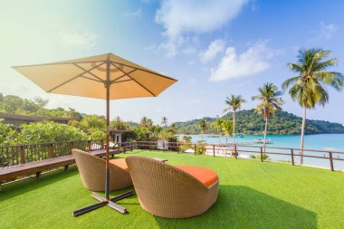 Rattan Tayland tropikal beyaz kum plaj yakınındaki en iyi yeşil çim katta daybed sandalye örgü. Ufuk ulaşan su ile aqua renkli.