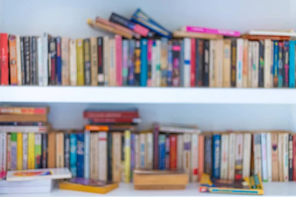 Abstract blurred modern white bookshelves with books, manuals and textbooks on bookshelves in library or in book store, for backdrop. Concept for education.