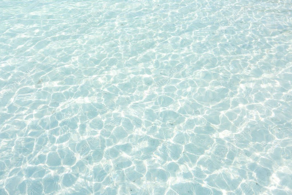 Crystal clear water of the tropical sea and white sand beach. Abstract water background. Sun light and clear sea water texture background.