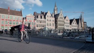 Kamera Grasbrug köprü Ghent erken bir bahar akşamı geçiş bisikletçiler göstermek için flok stil yükselir. Graslei arka planda olduğunu
