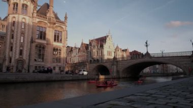 Kanocu altında Leie kanalda geçerken kamera jib stil Ghent Bridge'de St Michaels önünde yükselir. Bir bahar akşamı Altın ışık ile binalar üzerinde alınan.