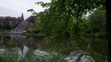 Kamera Minnewater ve Brugge, Belçika Kasteel sakin bahar sabahı ortaya çıkarmak için ağaç geçmiş slaytlar. 