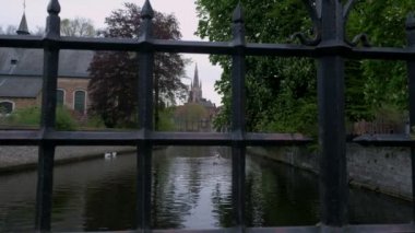 Katelijnestraat kanal, kuğu ve sivri, kilise, Meryem Bruges Brugge Belçika ortaya çıkarmak için parmaklıklar arkasında kamera yükselir