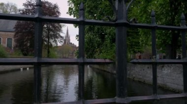 Katelijnestraat kanal, kuğu ve sivri, kilise, Meryem Bruges Brugge Belçika ortaya çıkarmak için parmaklıklar arkasında kamera yükselir