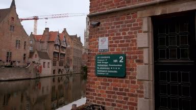 Katelijnestraat kanal ve çan kulesi Bruges arka planda ortaya çıkarmak için duvar arkasından kamera slaytlar. Bir bulutlu bahar gününde alınan