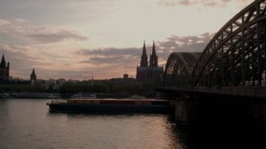 Hohenzollernbrucke ve Köln Katedrali Almanya'da statik klip gün batımında. Köprünün altında büyük bir mavna geçip