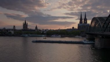 Mavna altında geçerken Hohenzollernbrucke ve Köln Katedrali için Almanya'da Ren günbatımında tava 