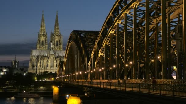 Statische Aufnahme der Hohenzollernbrücke und des Kölner Doms bei Nacht mit eingeschaltetem Licht. Blaue Stunde für Fußgänger