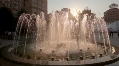 Kamera jib stil yavaş hareket arkadan aydınlatmalı müzik çeşme önünde yükselir. Bağımsızlık Meydanı, Kiev, Kiev, Ukrayna gün batımında