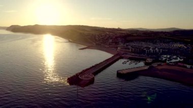Drone sırt--dan Batı Körfezi Dorset'deki / daki güzel gün batımı yavaş yavaş uçar. Liman ve şehir içinde atış vardır 