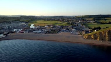 Drone yavaş beach West Bay Dorset'deki / daki doğru günbatımı sırasında uçar. Bridport ve Dorset kırsal arka planda 