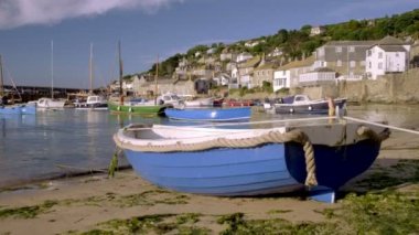 Mousehole Cornwall liman renkli balıkçı tekneleri ile ortaya çıkarmak için küçük tekne arkasında kamera yükselir 