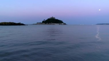 St Michaels Mount Cornwall görüntülerini düşük düzey drone ile dolunay. Dron küçük dalgalar ile aşağıdaki yavaş ve yana doğru uçar