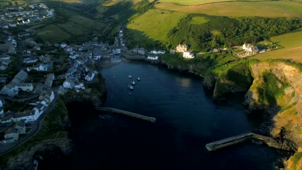 Drone pulls back at height to reveal the harbor of Port Isaac in Cornwall during the golden hour — Stock Footage Drone Pulls Back Height Reveal Harbor Port Isaac Cornwall Golden Stock Video