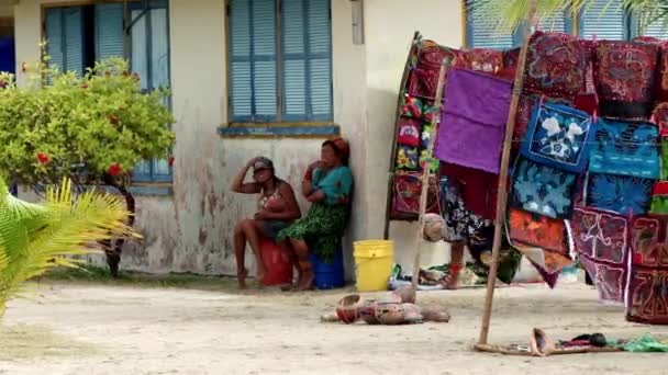 つの地元の女性がパナマのサンブラス諸島でエル ポルニベルに風に吹かれて 販売のカラフルな先住民族グナ マンボウのそばに座り — ストック動画