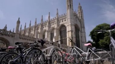 Fotoğraf makinesi, Cambridge 'deki Kings College Şapeli ortaya çıkarmak için döngülerin arkasındaki satırlardan yükselir. Çekim yoğun bir öğleden sonra yaz 2018