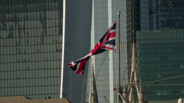 Londra'da Hms Belfast'ta uçan Union Jack'in yakın çekimi. Londra şehrinin gökdelenleri arka planda.