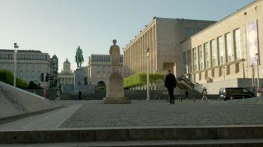 İş adamı bir bahar sabahı Belçika Kraliyet Kütüphanesi doğru Place de l'Albertine genelinde yürüyor