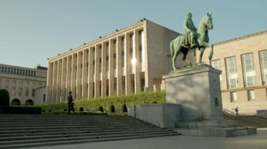 Arkasında Belçika Kraliyet Kütüphanesi ile Kral Albert I Heykeli geniş statik çekim. İnsan yürürken bir bahar sabahı alınan