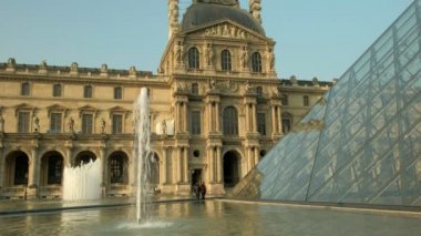 Paris/Fransa - 30 Nisan 2019: Louvre Piramidi ve çeşmelerin statik orta klibi. Altın ışıkta sabahın erken saatlerinde çekilmiş