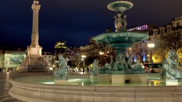 ポルトガルのリスボンのロッシオ広場で背景にペドロIvの柱と照らされた噴水の傾き — ストック動画