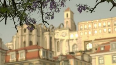 Lizbon 'daki Carmo Manastırı' nın defocus klipsi. Rossio Meydanı 'ndaki Jacaranda çiçeği çerçeveli. Sabah altın saatinde çekilen
