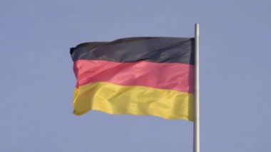 Berlin 'deki Reichstag Binası' nın üzerinde sert esintiyle dalgalanan büyük Alman bayrağının ultra yavaş çekim klibi