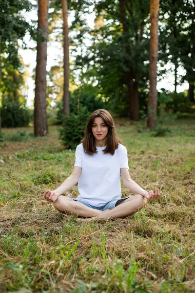 Ormanda gözleri açık meditasyon yapan bir kız. Dikey resim
