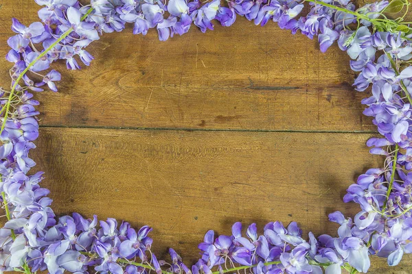 Beautiful frame of blooming purple wisteria on vintage wooden ba