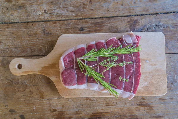 Hermoso trozo salado de carne de res con romero en la tabla de cortar — Foto de Stock