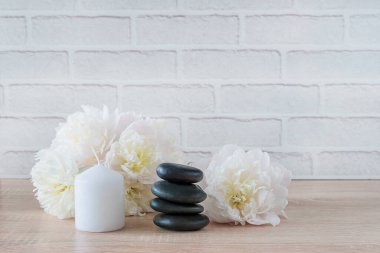 Güzel bir spa ve rahatlama kompozisyonu. Siyah masaj taşları, beyaz şakayıklar ve mum.