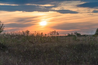 Gün batımının ufukta göründüğü güzel bir kırsal alan.