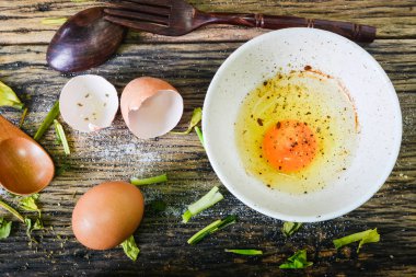 Üstten görünüm, ahşap bir masa üzerinde bir kapta çiğ yumurta. Yumurta çok pişirmek için kullanılabilir.