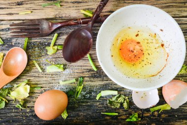 Üstten görünüm, ahşap bir masa üzerinde bir kapta çiğ yumurta. Yumurta çok pişirmek için kullanılabilir.