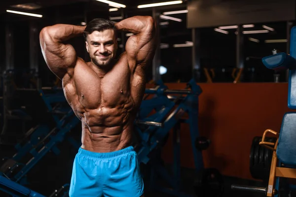 Handsome young fit muscular caucasian man of model appearance workout training in the gym gaining weight pumping up muscle, poses, drinks water  fitness and bodybuilding sport nutrition concept